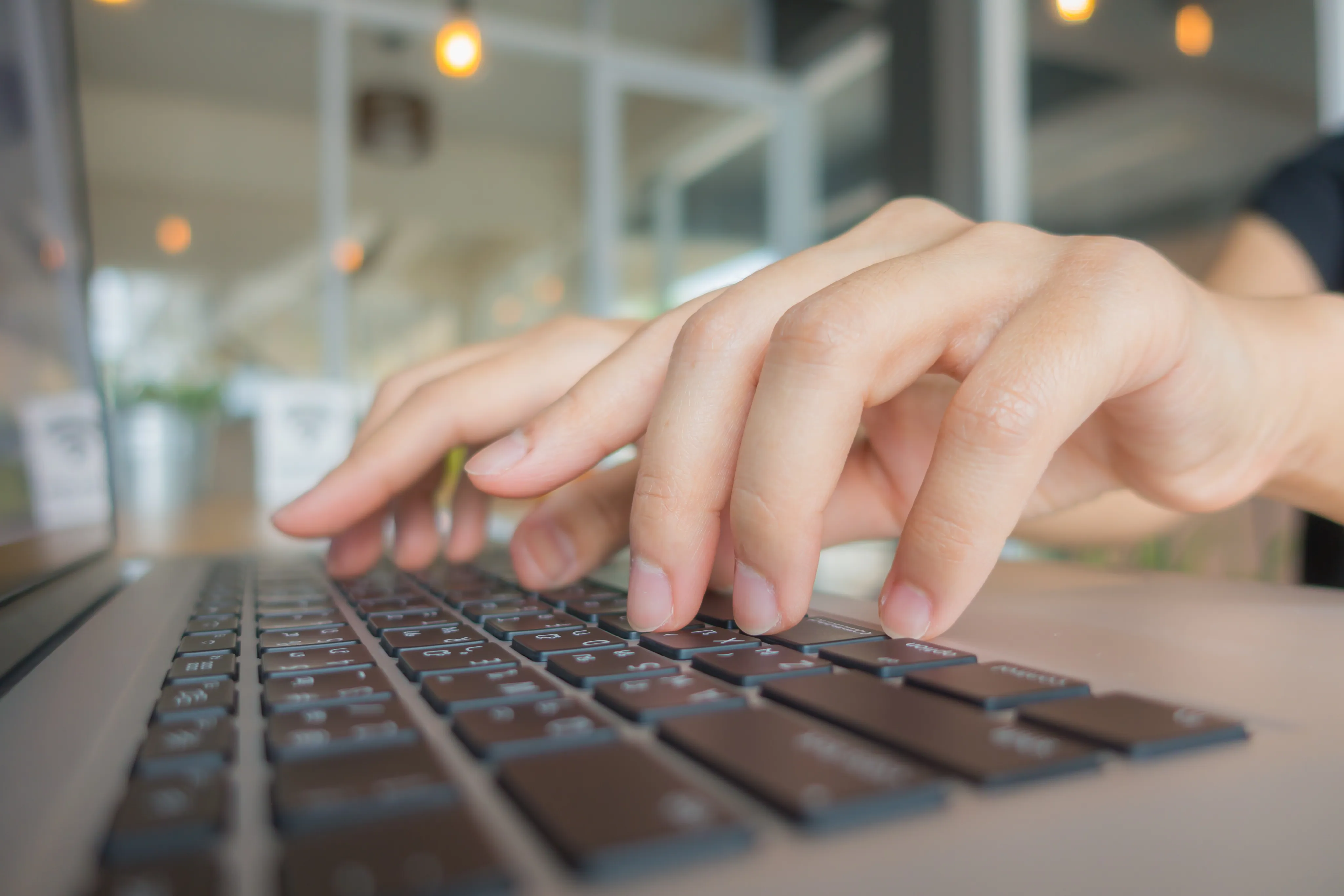 Manos escribiendo sobre un teclado en un entorno de oficina