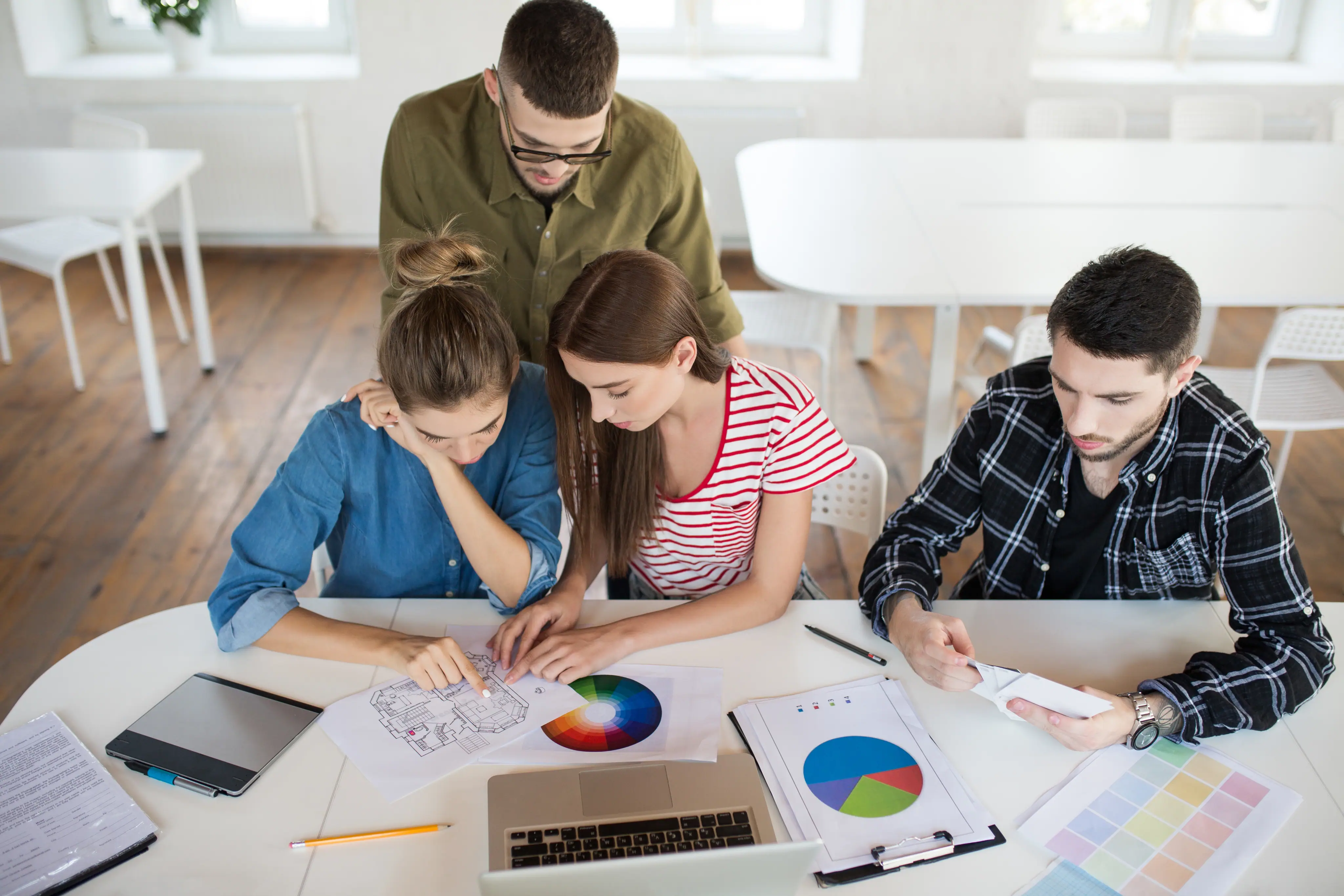 Equipo colaborando alrededor de una mesa de trabajo con métricas y gráficos